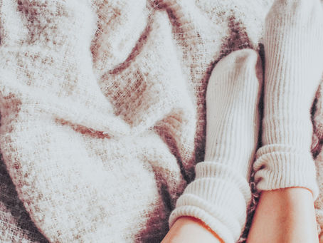 Woman wearing warm socks in bed as part of a Chinese medicine fertility wellness routine.