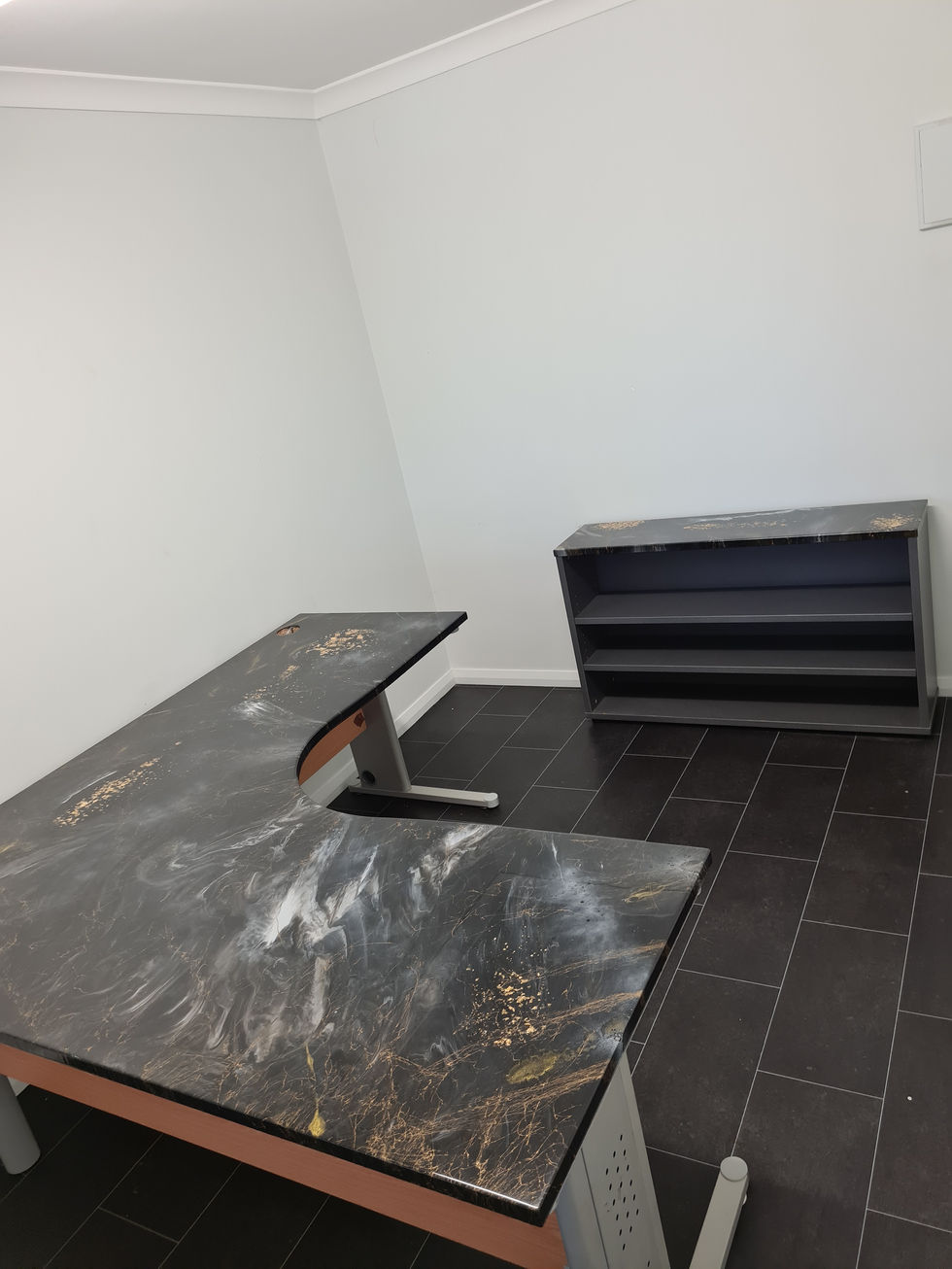 Empty office space with a desk and bookshelf against white walls
