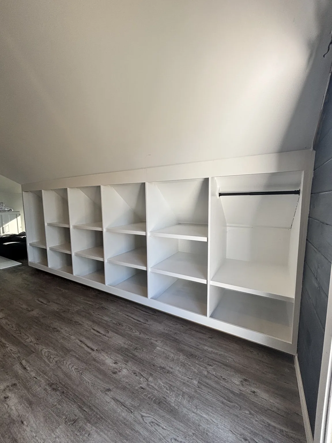 Open shelving and hanging space fitted beneath a sloped ceiling