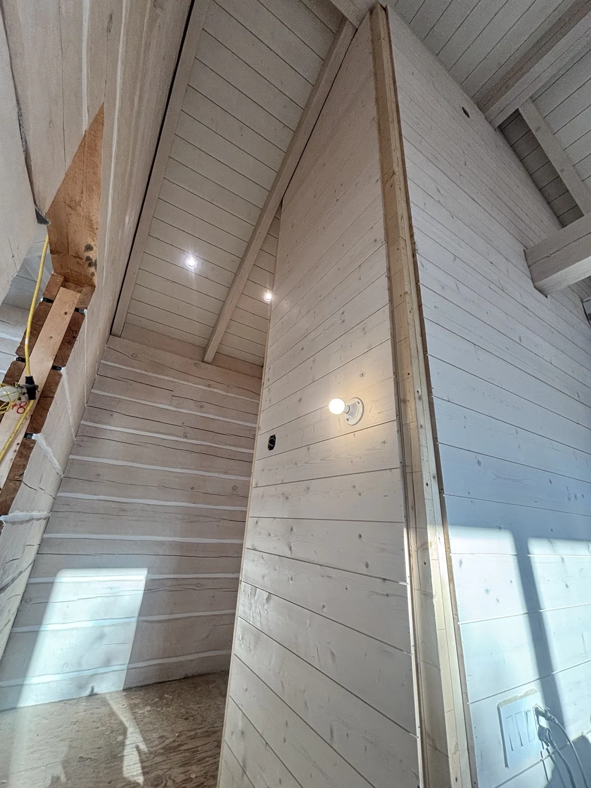 Ceiling boards and wall panelling meeting around exposed timber beams