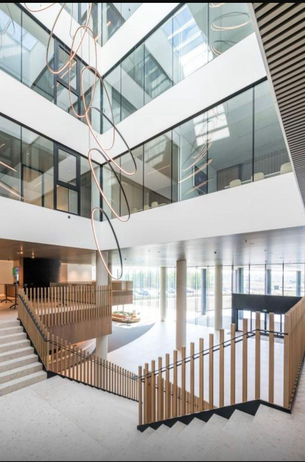 Modern light-filled interior atrium with glass, wood railings and sculptural lighting