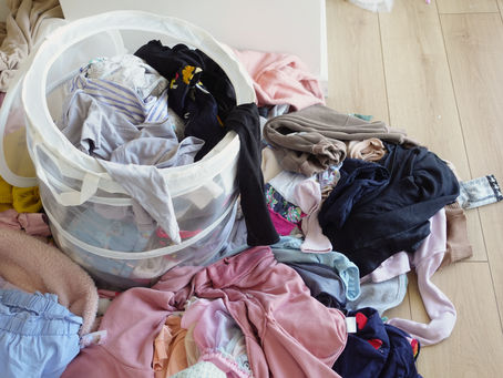 clothes pile next to laundry basket