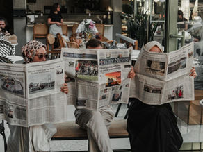 três pessoas lendo jornal