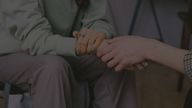 Two people holding hands, offering comfort and support