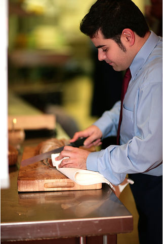 A waiter cutting bread 