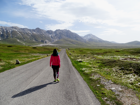 donna che cammina lungo la strada di Campo imperatore con sfondo Monti della Laga