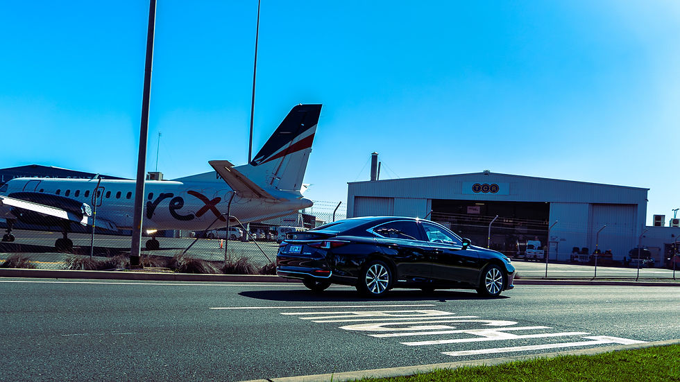 A black Lexus sedan waiting at Adelaide Airport with an aircraft behind it