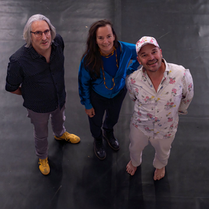 Drei Personen stehen auf einem schwarzen Tanzboden und lächeln zur Kamera hinauf. Es handelt sich um Tobias Stiefel, Jana Korb und Hoppe Hoppinsky.