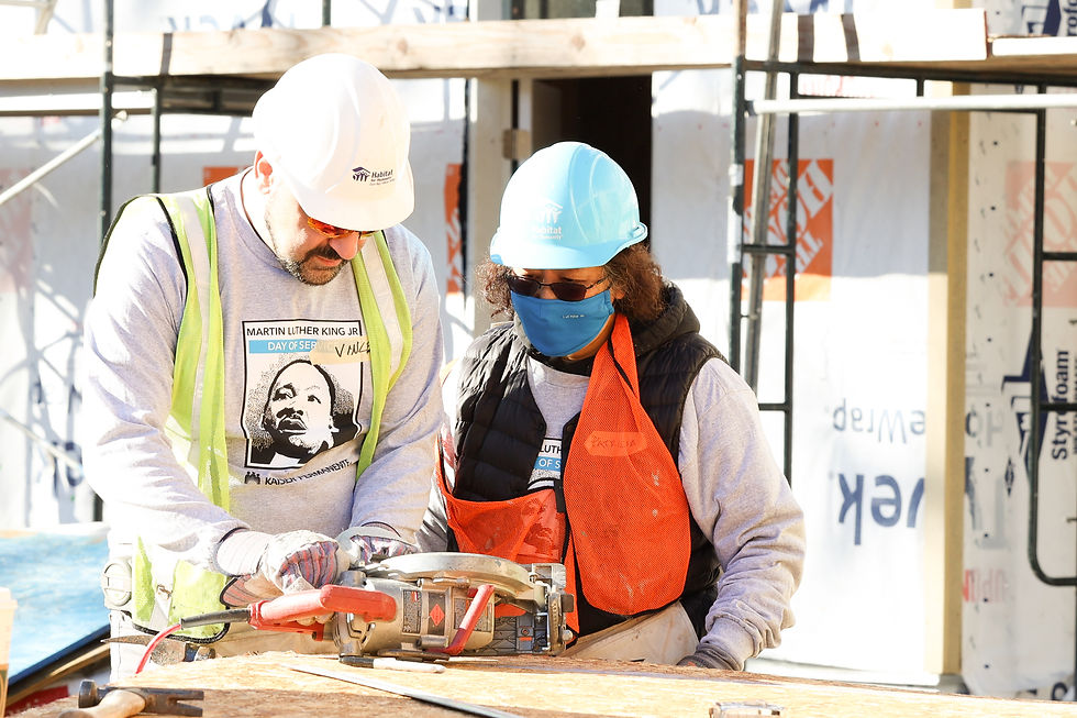Two Kaiser Permanente volunteers work side by side using a saw