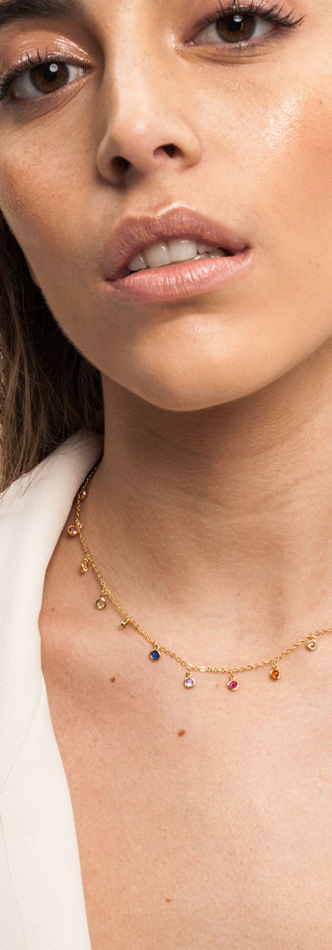 Fotografia de modelo de joyas (mujer) con traje blanco y joyería dorada sobre fondo beige