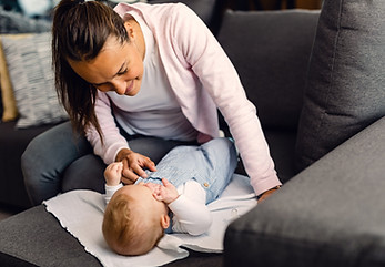 young-smiling-mother-taking-care-her-baby-boy-who-is-lying-sofa.jpg