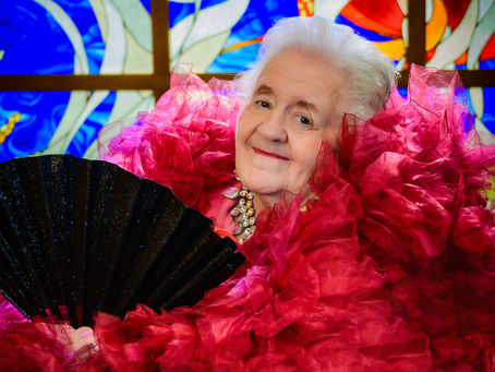 Elderly woman in glam wardrobe, smiling.