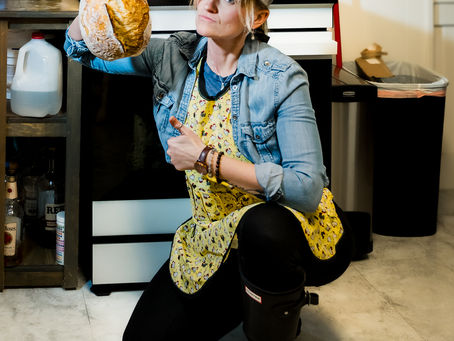 Woman posing with sourdough bread giving a thumbs up.