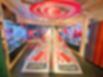 Galleria Campari in Milan display with a triangular Campari-themed structure covered in logos. Background features colorful walls and glass cabinets. Vibrant mood.