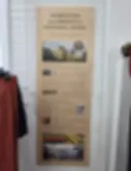 Sign promoting Pendleton's support for America's National Parks on a wooden board with images. Hanging beside red clothing and a white pipe at the Pendleton Woolen Mill Tour Washougal store.