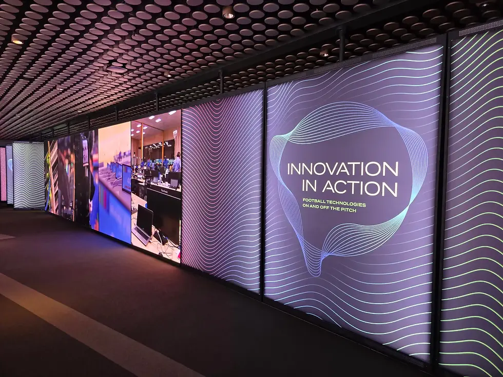 Futuristic corridor with glowing digital panels reading INNOVATION IN ACTION, showcasing football technology displays.