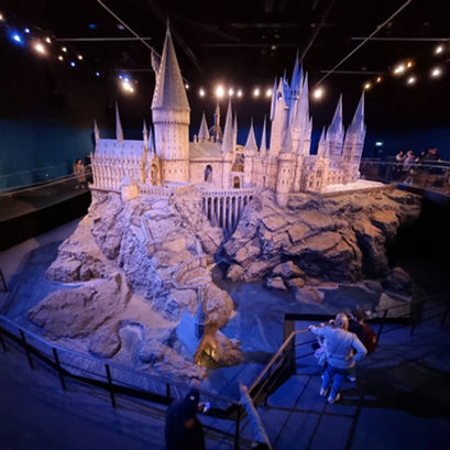 Hogwarts castle model illuminated in a dark room at the warner bros. studios tour london, harry potter studio tour visitor centre experience
