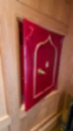 Red wall safe with gold handle, partially open in wooden panel wall. Gold emblem on door. Warm tones and secure, secretive ambiance at strathisla distillery.
