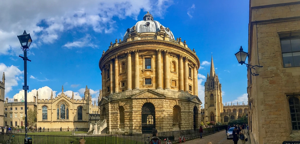 Historic round building, Radcliffe Camera, under a bright blue sky. People walk nearby. Gothic architecture in the background.