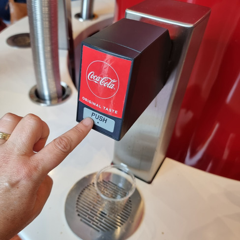 a finger presses a button on a soda dispenser saying original taste