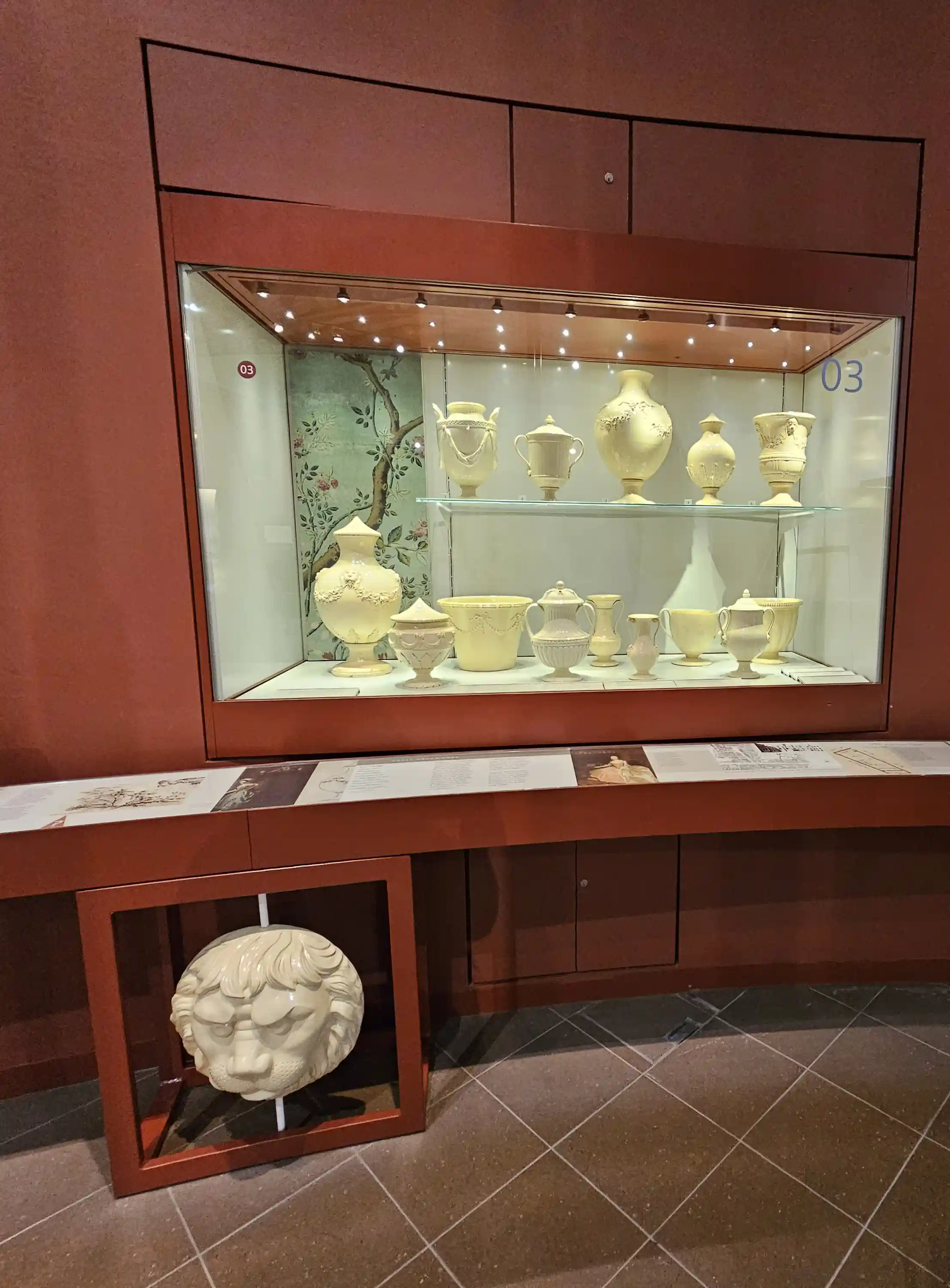 World of Wedgwood V&A Museum exhibits in a glass display case on a red painted wall, with a lion's head in white model, which is on a pole so it can be rotated by the public