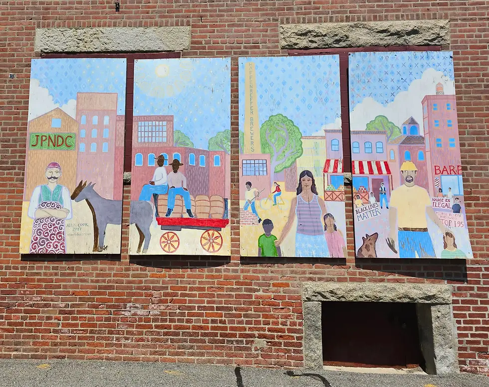 Mural on brick wall features diverse people, a cart, and text like JPNDC, Black Lives Matter. Bright colors and urban setting outside the Samuel Adams Boston Brewery.