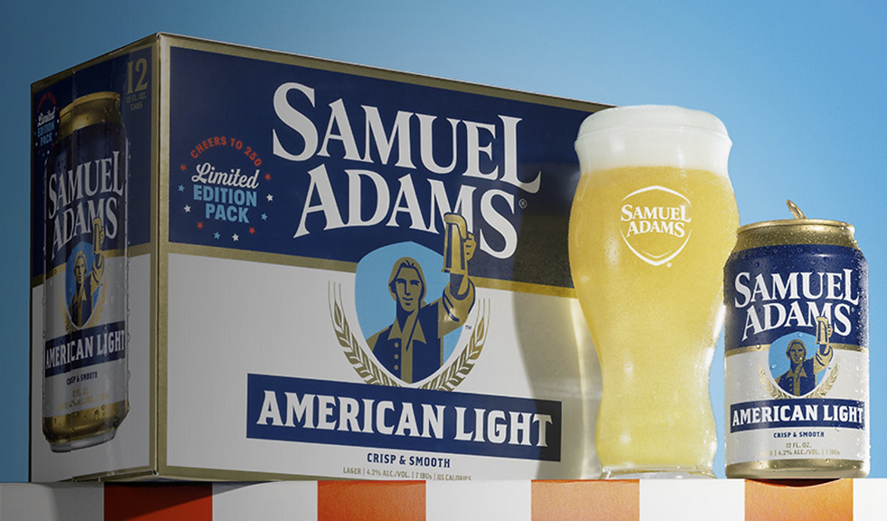 A Samuel Adams American Light box, pint glass with foam, and can on a striped surface against a blue sky. Text: Cheers to 250 Limited Edition.