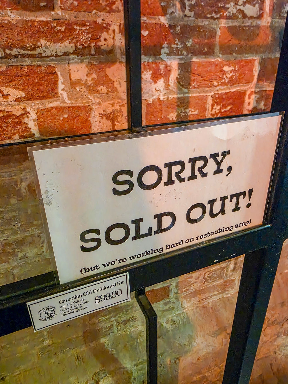 White sold-out sign on a brick wall reads SORRY, SOLD OUT! with smaller note about restocking and a $99.90 kit price at the Spirit of York Distillery in Toronto