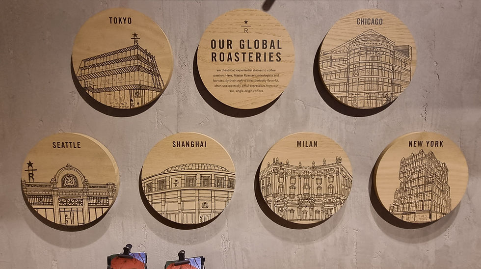 Seven wooden discs on a wall show illustrations of Starbucks roasteries in Tokyo, Chicago, Seattle, Shanghai, Milan, and New York.