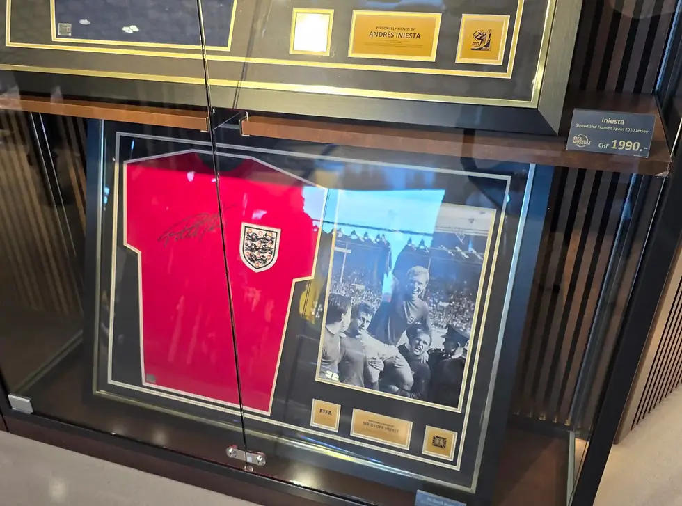 Framed signed football jerseys and photos in a glass display, including Iniesta and Geoff Hurst, with price tags at Fifa Museum in Zurich.