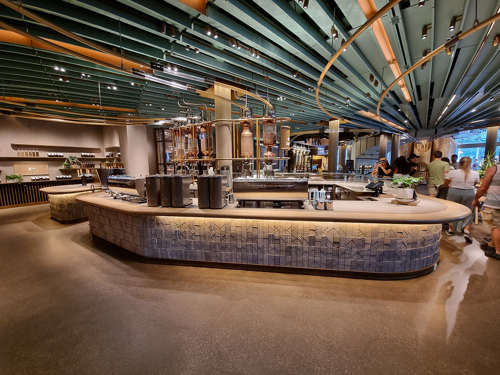 Modern coffee shop interior with green-striped ceiling, large curved counter, coffee machines, and people in casual attire. Warm, inviting atmosphere.