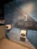 Exhibit wall titled "Creating a Masterpiece" with text and two protruding viewing devices at the Silverstone museum. Blue-toned mural of nature and architecture.