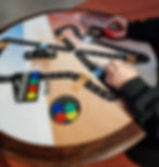 Hands playing a board game on a racetrack-themed table. Dice, colored markers, and game instructions visible. Warm lighting.