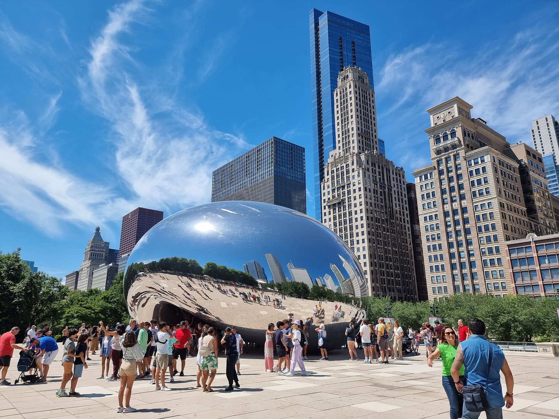 the silver metallic bean sculpture in chicago reflecting people standing next to it