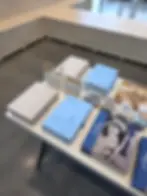 Books with blue and beige covers titled "World of Wedgwood" on a white table, surrounded by pens and pamphlets in a modern showroom.