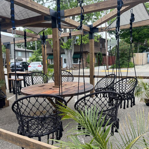 black cord swinging chairs are suspended from a wooden frame outside the tasting room