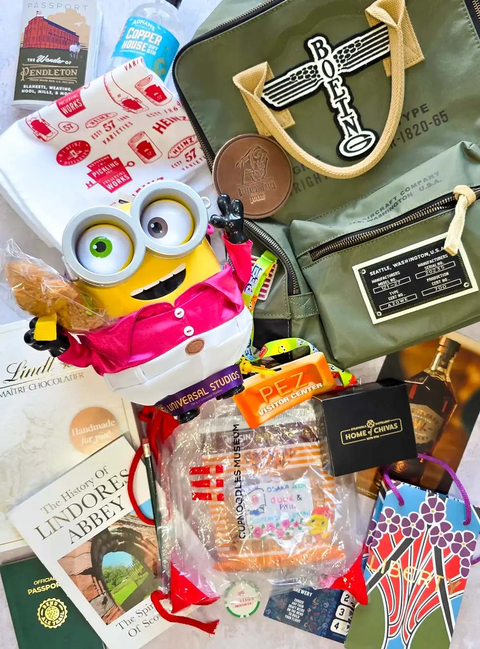 Assorted souvenir items, including a Minion toy, Boeing bag, and various books and candies, are arranged. Text includes "PEZ Visitor Center."