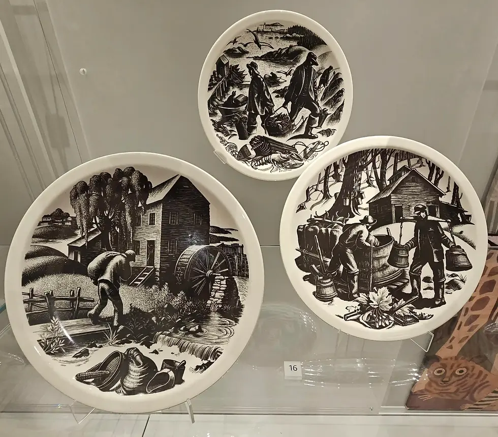 Three black-and-white plates depict rural scenes: a mill by a stream, people collecting barrels, and farmers in fields. Displayed in a glass case at the World of Wedgwood V&A Museum.