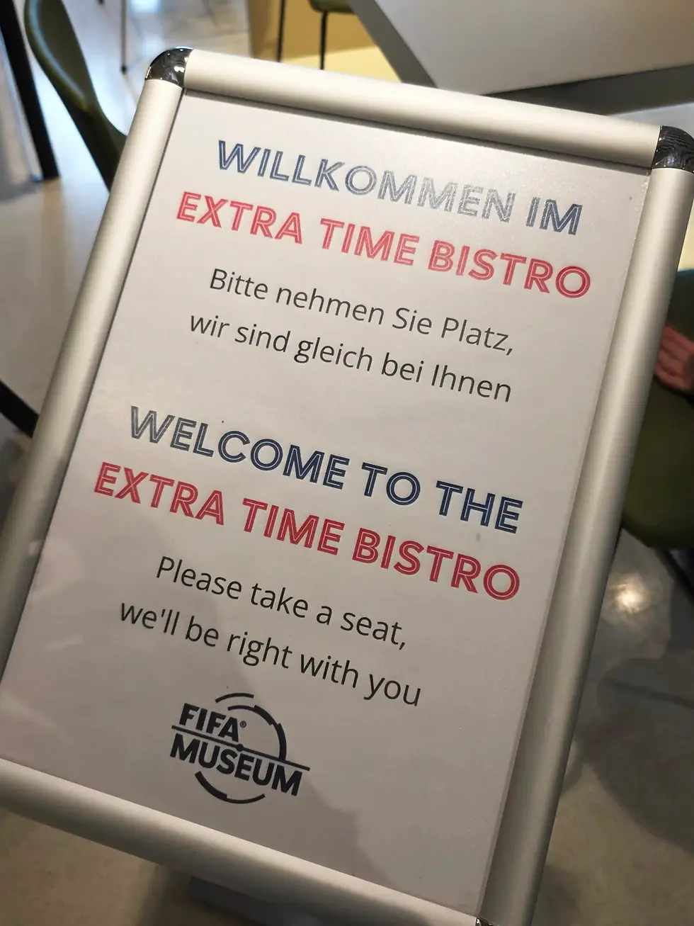 FIFA Museum sign in German and English welcomes visitors to Extra Time Bistro and asks them to take a seat.
