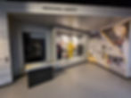 Exhibit on personal safety in motorsport at Silverstone museum, showcasing protective gear in a glass case, with racing suit displays and an info panel on materials.
