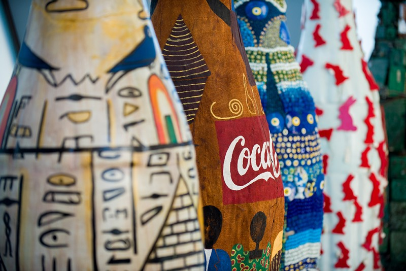 Colorful, patterned Coca-Cola bottle sculptures with various designs, including hieroglyphics and red bunnies, in a vibrant, artistic setting at World of Coca-Cola