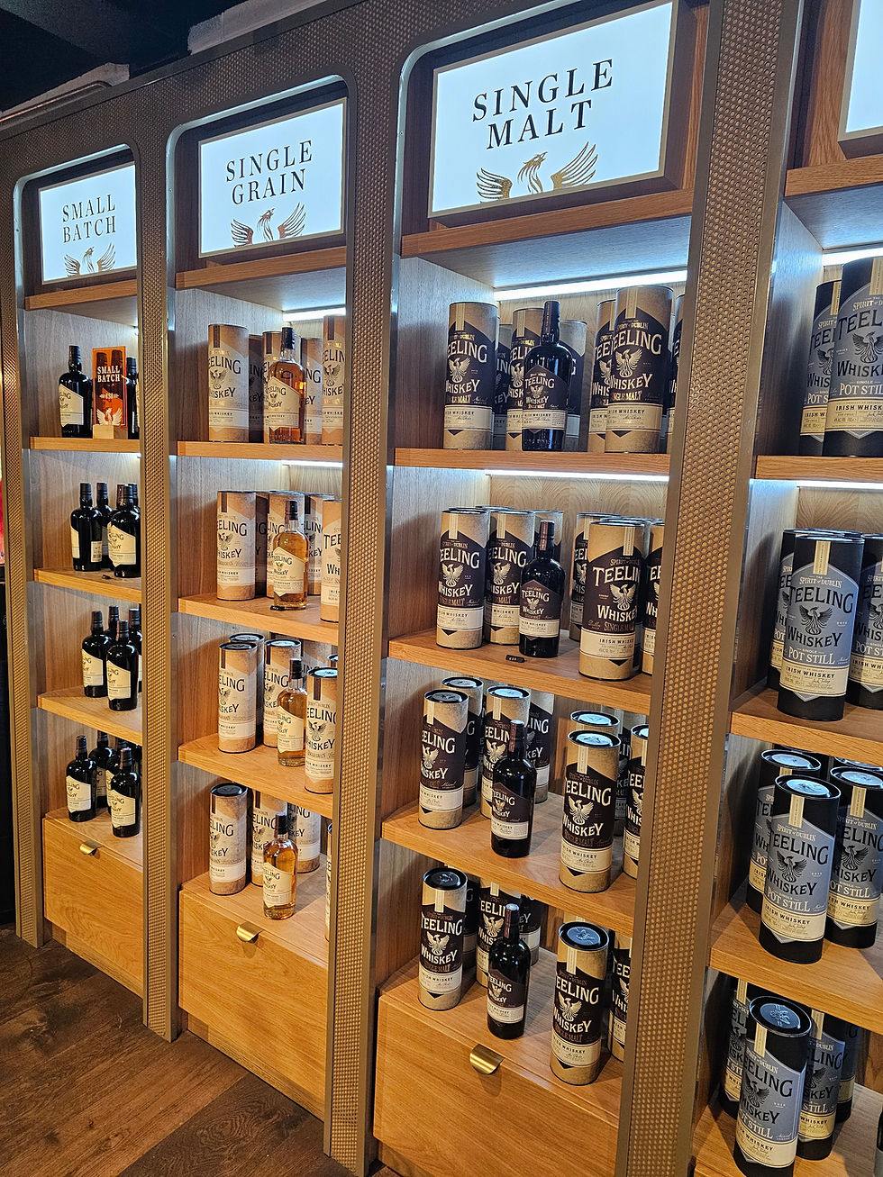 a wood and metal shelving system holds bottles of whiskey in the teeling shop