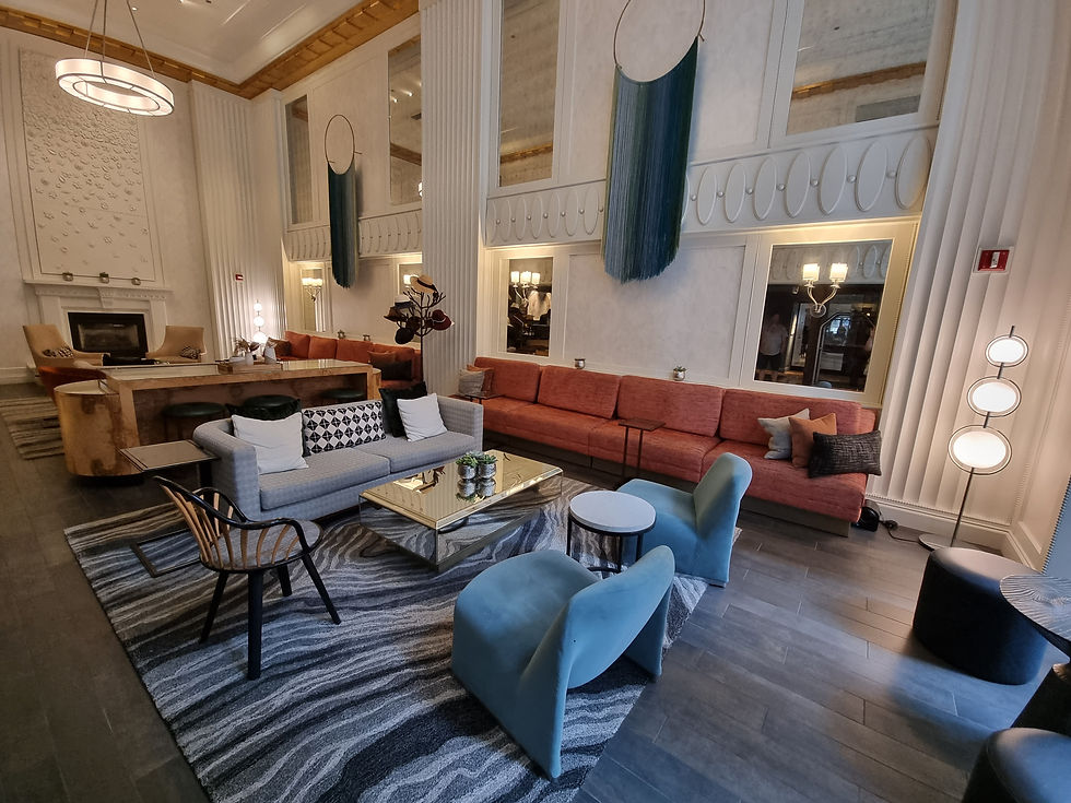 Modern lounge with blue, gray, and orange seating, geometric rug, and circular wall decor. Warm lighting creates a cozy atmosphere.