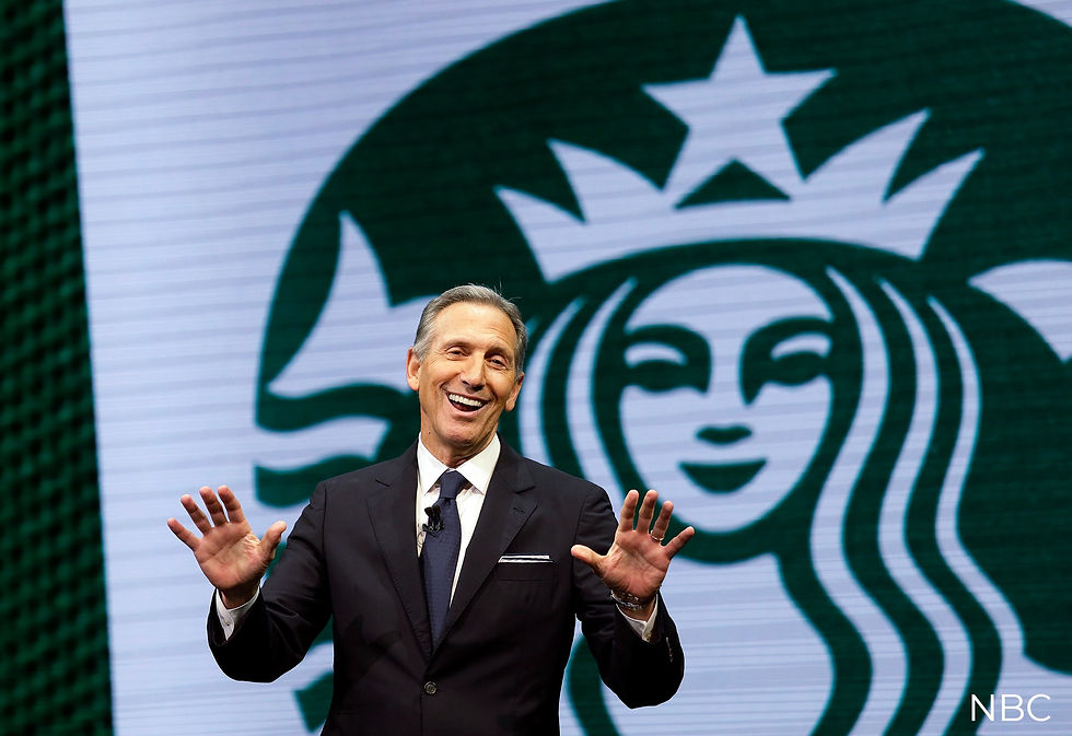 Howard Shultz smiling in a suit gesturing with hands, standing in front of a large Starbucks logo. Green and white background creates a lively mood.
