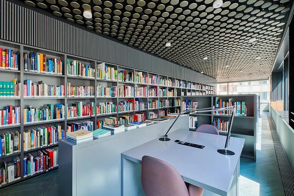 Modern library at the FIFA Museum with colorful bookshelves, empty study desk, and patterned ceiling in a bright windowed room.