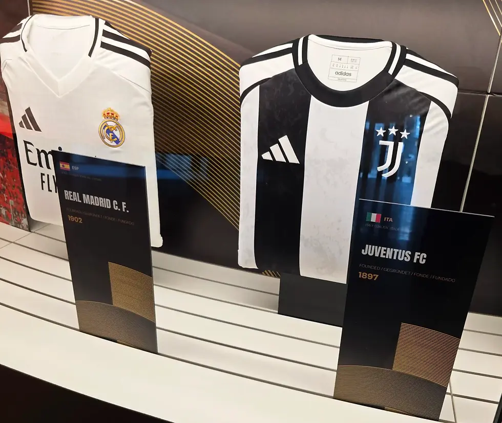 Real Madrid and Juventus Adidas jerseys displayed on stands in a museum gallery at Fifa Museum in Zurich, with team names and founding years visible.