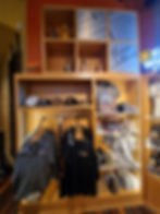 Store display with bourbon bottles, hats, shirts, and merchandise featuring Evan Williams branding. Warm lighting and organized shelves.