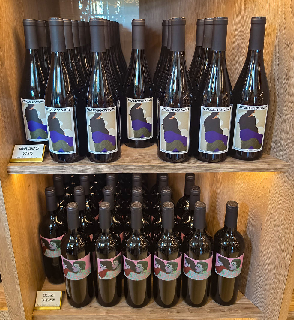 Rows of dark wine bottles on wooden shelves, labeled Shoulders of Giants and Cabernet Sauvignon, in a neat store display at Rosewood Winery.