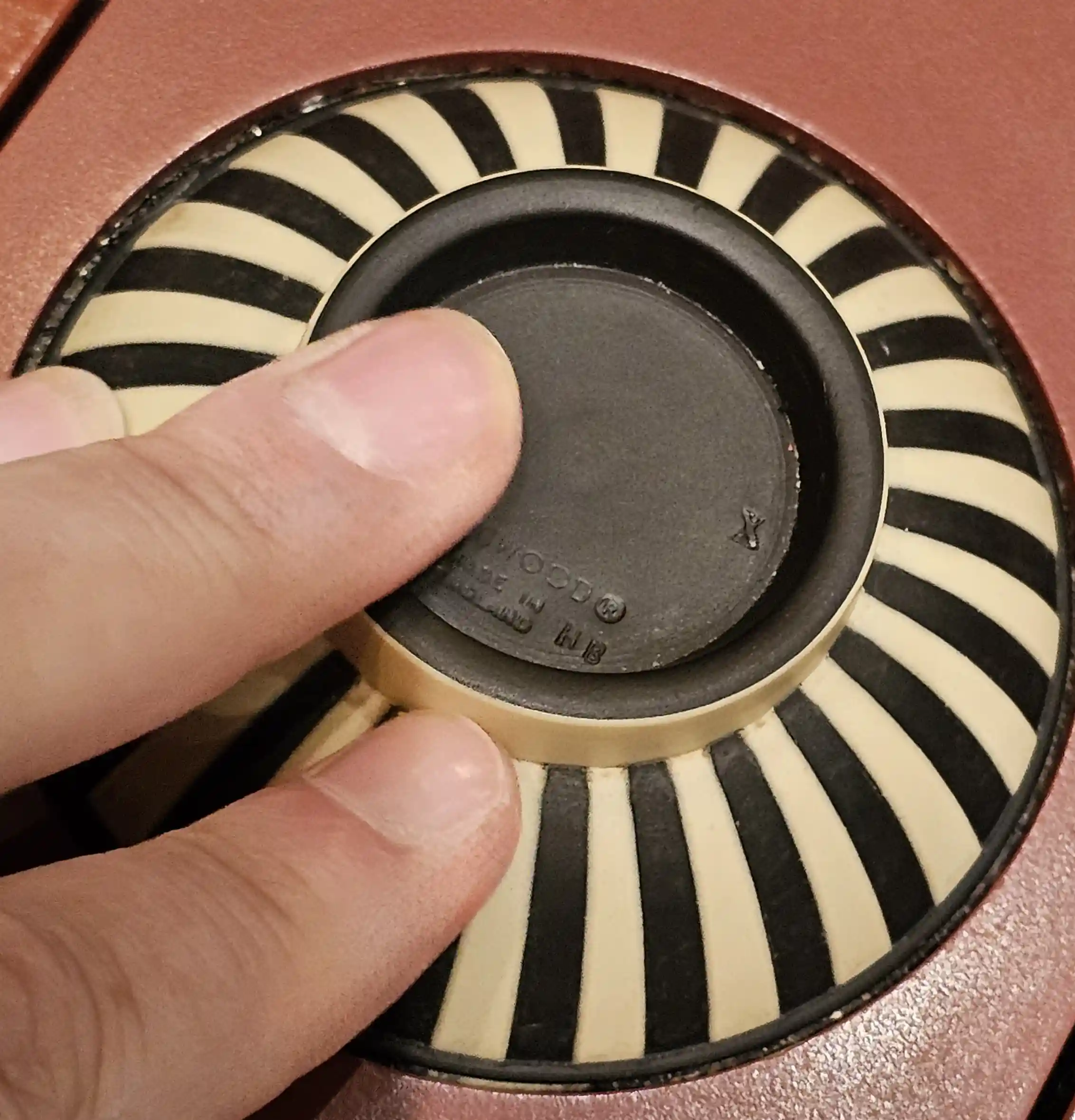 Hand with fingers pushing a black and white piece of upturned pottery at the World of Wedgwood V&A Museum