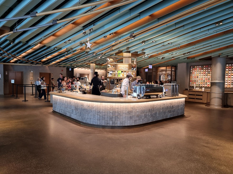 Modern cafe with a curved counter, staff preparing drinks, and customers waiting. Ceiling with teal beams, bright star decor, cozy ambiance.
